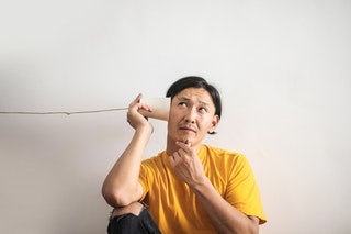 Man listening to a paper cup phone